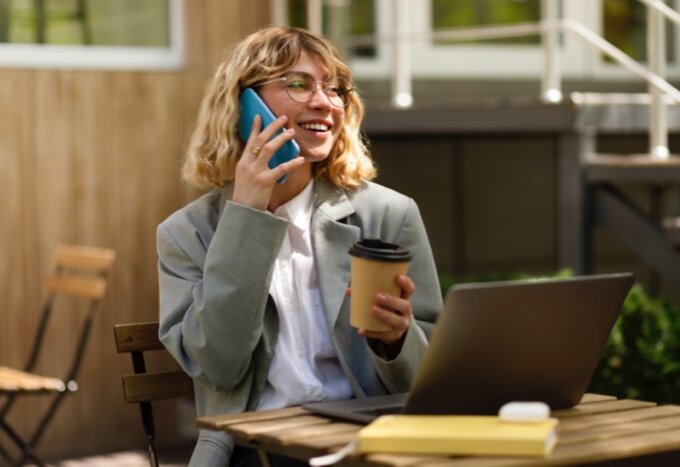 Jeune femme au téléphone avec un café - Experts en assurances - Ellipse Assurances