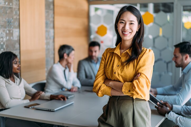 Professionnelle debout devant une table de conférence - Assurance collective en entreprise - Ellipse Assurances